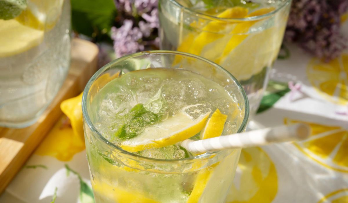 Gros plan sur un verre de citronnade avec rondelles de citron et feuilles de mélisse