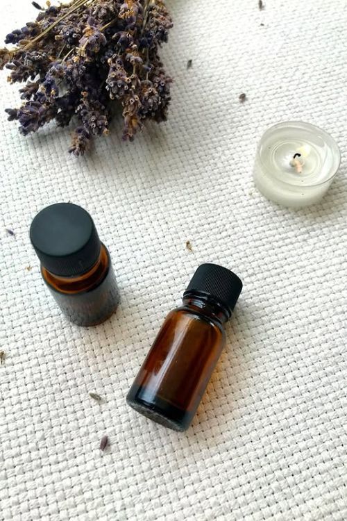deux bouteilles d'huiles essentielles sur un table et un bouquet de lavande 