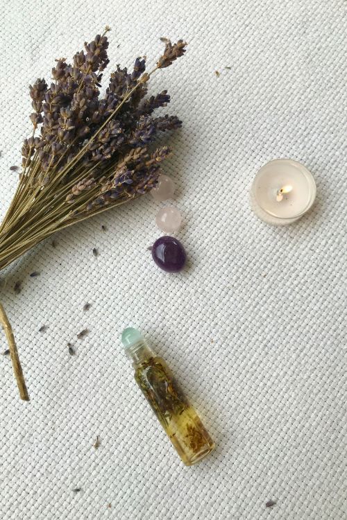roll on en flat lay sur une nappe blanche, bougie et bouquet de lavande